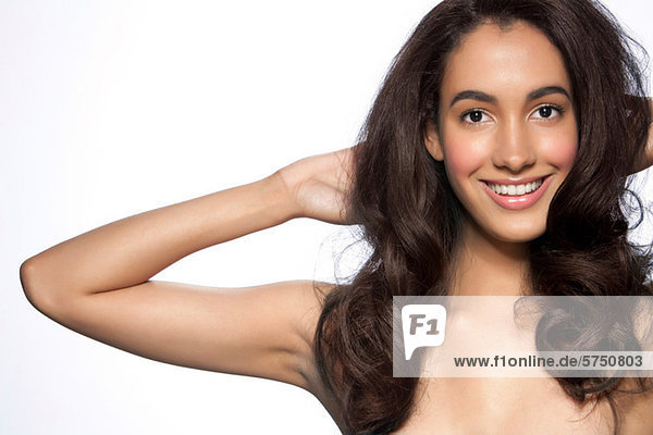 Young woman with hands in hair against white background