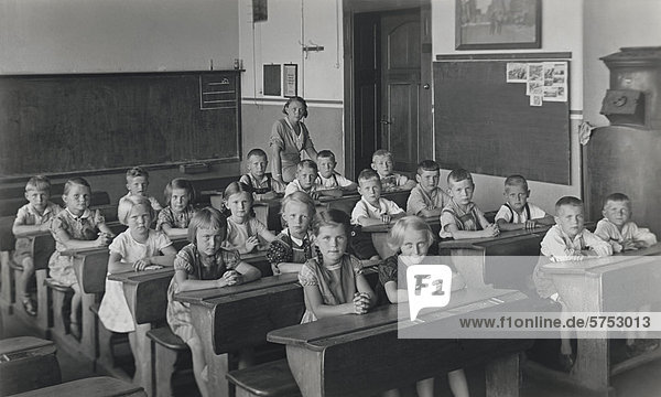 Historische Aufnahme von Schülern mit Lehrerin im Klassenzimmer
