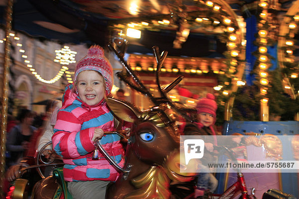 Dreijähriges Mädchen fährt Karusell auf dem Weihnachtsmarkt