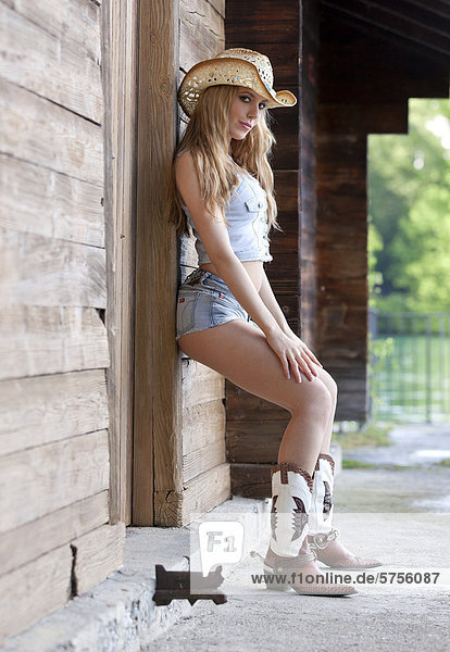 Young woman in jeans hot pants  jeans top  hat and cowboy boots  western style