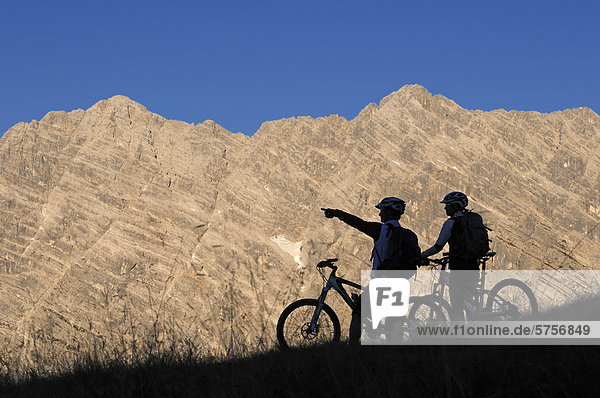 Mountainbikers in front of the East Face of Mt Watzmann  from Mt Feuerpalven  Berchtesgadener Land district  Upper Bavaria  Bavaria  Germany  Europe