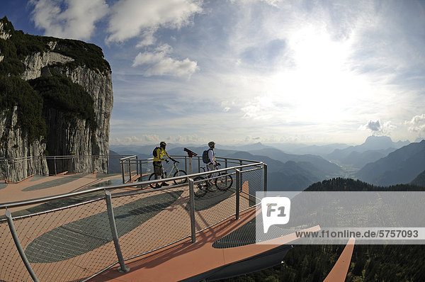 Mountain bikers standing on an observation deck with a see-through floor  Triassic Park  Steinplatte mountain  Waidring  Tyrol  Austria  Europe