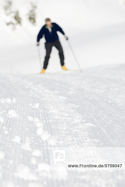 Detail eine präparierte Langlaufloipe mit einer männlichen Skifahrer im Hintergrund. Strathcona Provincial Park  British Columbia  Kanada.