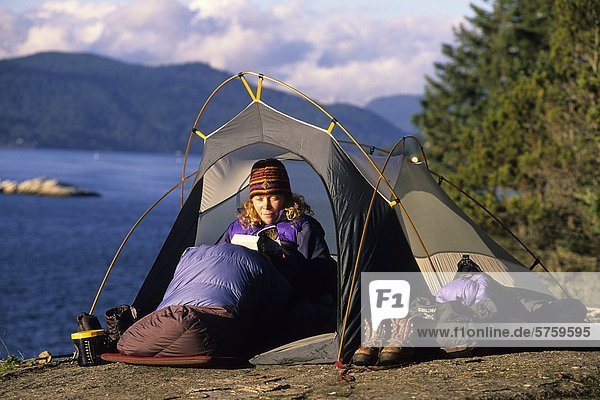 Woman reads a book in her tent  Lighthouse Park  West Vancouver  British Columbia  Canada.