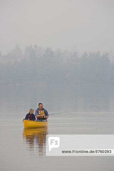 Young/middle-aged man fishing with son from canoe on Source Lake  Algonquin Provincial Park  Ontario  Canada.