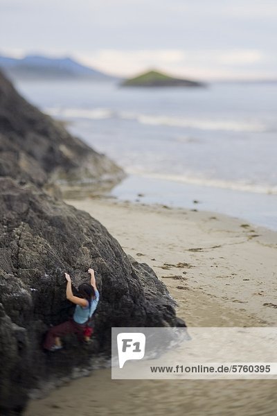 A young female bouldering oceanside in Tofino  Vancouver Island  British Columbia  Canada