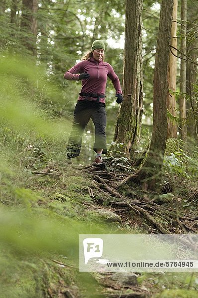 Young woman running on the Diez Vistas Trail. Buntzen Lake Regional Park. Port Moody  British Columbia  Canada