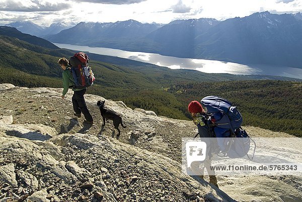A young couple with their dog and baby hiking on a ridge in the Potato Range with Tatlayoko Lake below  Chilcotins  British Columbia  Canada