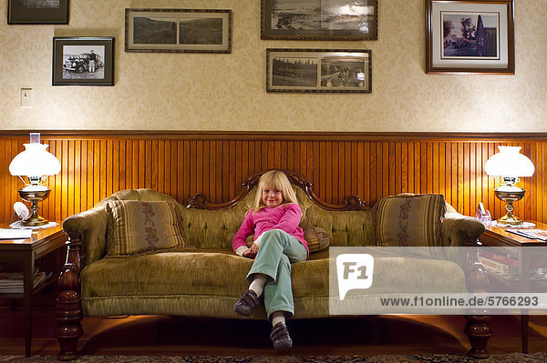 Five year old girl on antique sofa. Quilchena hotel  British Columbia  Canada.