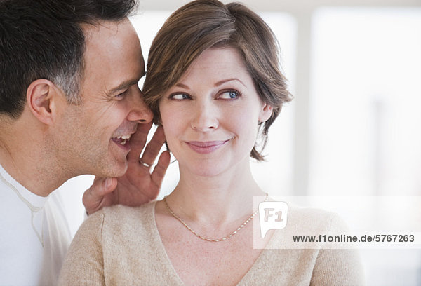 Man whispering to woman's ear
