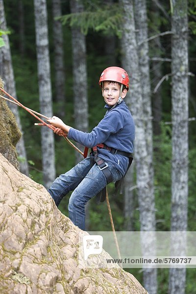A young boy rappells down a cliff-face at Horne Lake's outdoor climbing area  near Qualicum Beach  Central Vancouver Island  British Columbia  Canada.