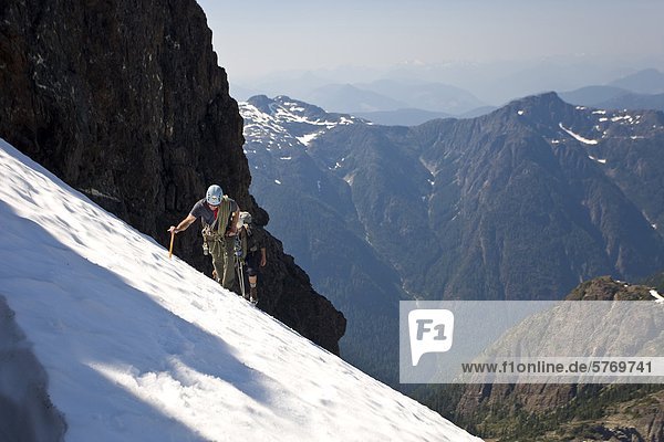 Zwei Bergsteiger aufsteigen ein Snowpatch dem Weg an die Spitze der Elkhorn Mountain im Strathcona Park  Vancouver Island  Kanada.