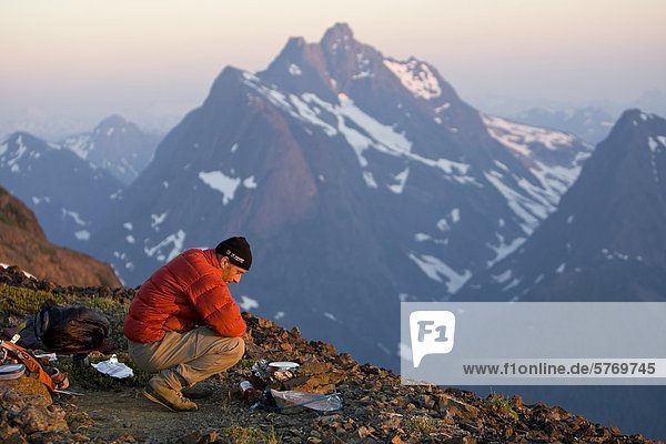 A lone climber prepares dinner while setting up camp on Elkhorn Mountain. Strathcona Park  Central Vancouver Island  British Columbia  Canada