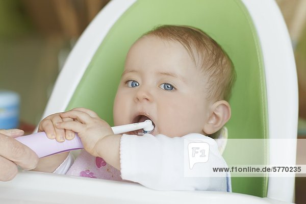 Weibliches Baby im Hochstuhl putzt die Zähne