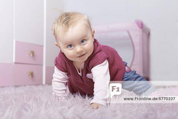 Weibliches Baby krabbelt auf einem Teppich