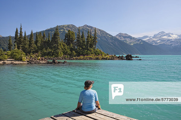 Woman relaxing on the shore of Garibaldi Lake in Garibaldi Provincial Park  British Columbia  Canada.