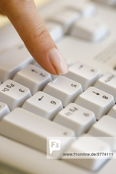 Woman pressing number key on computer keyboard
