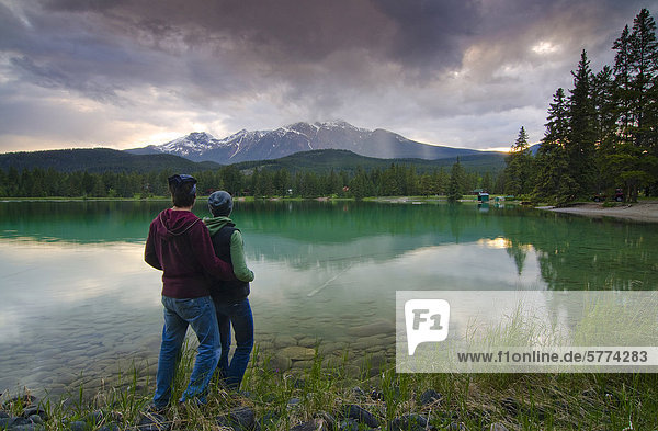 Couple enjoy the view of Lake Edith and Mount Pyramid in the Rocky Mountains  near Jasper  Alberta  Canada