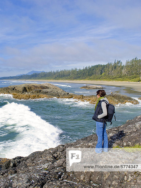 Young women hiker enjoys her view of crashing waves approaching Long Beach  near Tofino  Pacific Rim National Park  Vancouver Island region  British Columbia  Canada