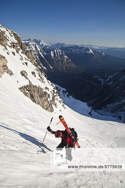 A man bootpacks up the steep and exposed Northface of Mt Stanley  Kootenay National Park  British Columbia  Canada