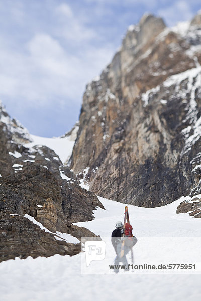 A male backcountry skiers bootpack up a steep spring couloir. 3/4 couloir  Moraine Lake  Banff National Park  Alberta  Canada