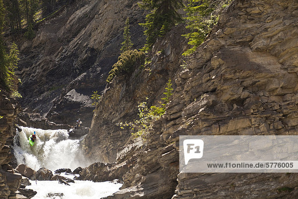 A male whitewater kayaker blasts through a waterfall on the Big Horn River  Nordegg  Alberta  Canada