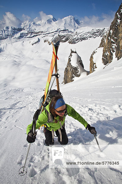 A female backcountry skier bootpacks up a steep slope while on a backcountry ski hut trip in the canadian rockies near Golden  British Columbia  Canada