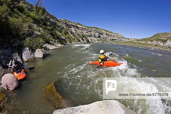 A female kayaker eddys out into the main flow of the warm and fun grade 3-4 St Mary's River  Alberta  Canada