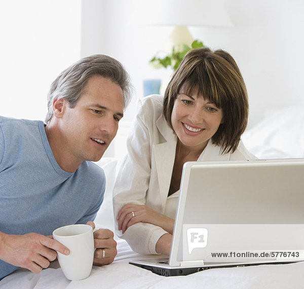 Couple looking at laptop on bed