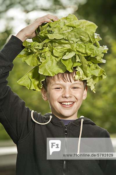 Junge mit Salaternte auf dem Kopf
