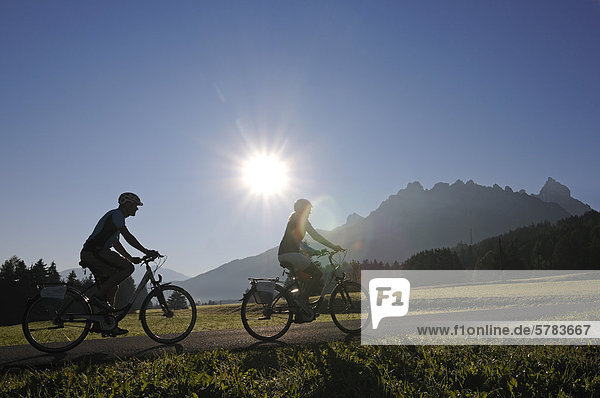 Couple riding electric bicycles  Innichen  Hochpustertal valley  Province of Bolzano-Bozen  Italy  Europe