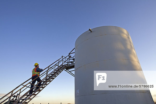 Öl Industrie Worker auf Storage Tank-Plattform am Telefon sprechen.