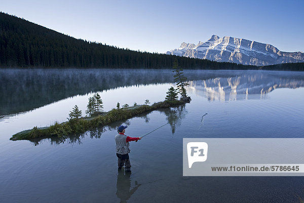Middle aged male fly fishing in Two Jack Lake  Banff National Park  Alberta  Canada.