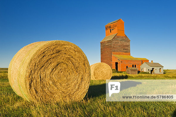 old grain elevator and round hay bales   ghost town of Neidpath  Saskatchewan  Canada