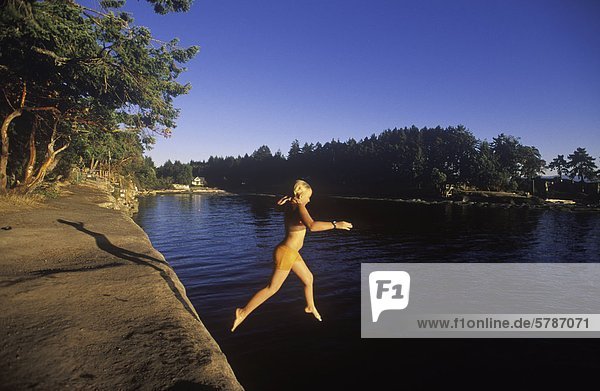 Malaspina Galleries  Gabriola Island  Young girl jumping from sandstone ledge  Vancouver Island  British Columbia  Canada.