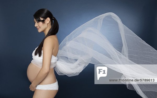 Stehende schwangere Frau in ein Tuch gewickelt