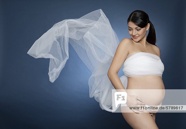 Stehende schwangere Frau in ein Tuch gewickelt