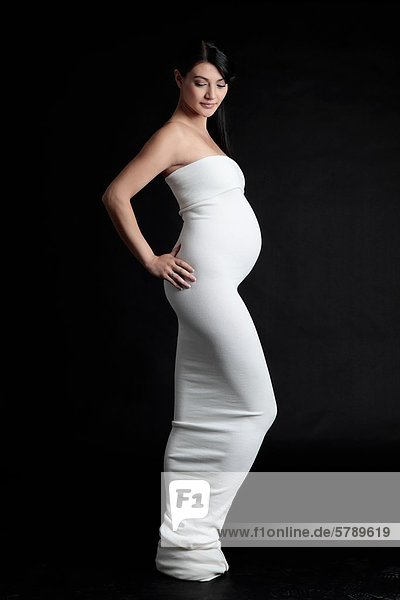 Stehende schwangere Frau in elegantem Kleid