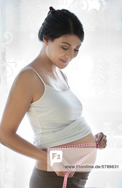 Schwangere Frau misst ihren Bauchumfang