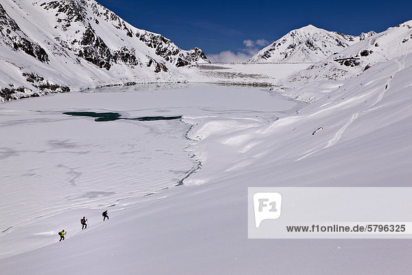 Cross-country skiers in front of a reservoir  Kuehtai valley  Stubai Alps  Tyrol  Austria  Europe