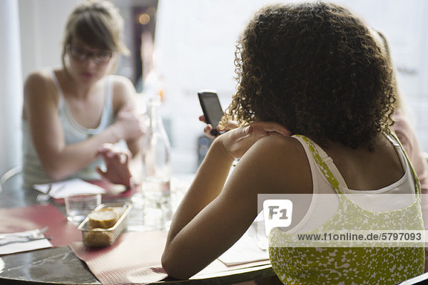 Junge Frau SMS im Café  Rückansicht