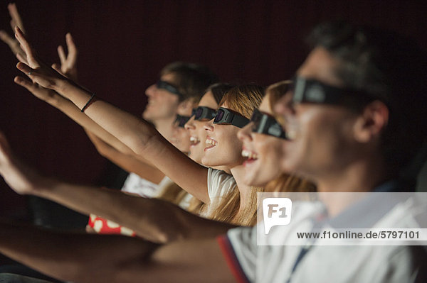 Publikum mit 3-D-Brille im Kino  Arme ausstreckend