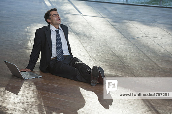 Businessman relaxing on deck with laptop computer