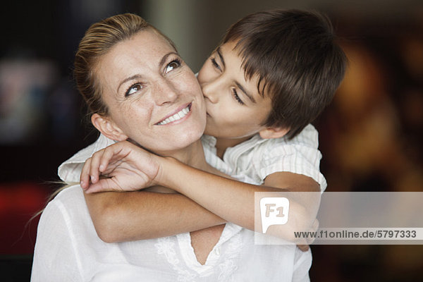 Junge  der die Wange seiner Mutter küsst.