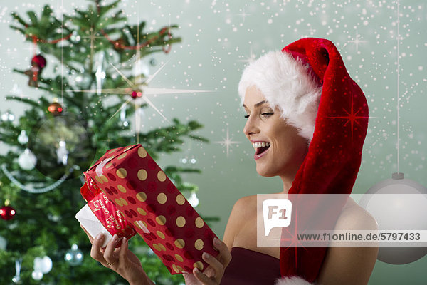 Frau mit Weihnachtsmütze  Weihnachtsgeschenke anschauen