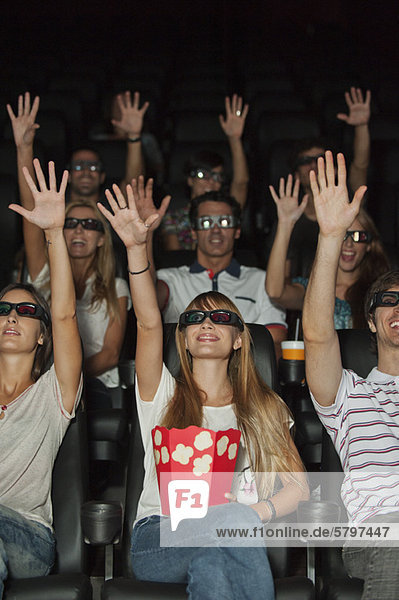 Publikum mit 3-D-Brille im Kino  Arme nach oben reichend