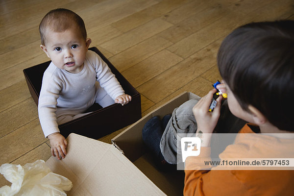 Junge und kleine Schwester beim Spielen in Kartons