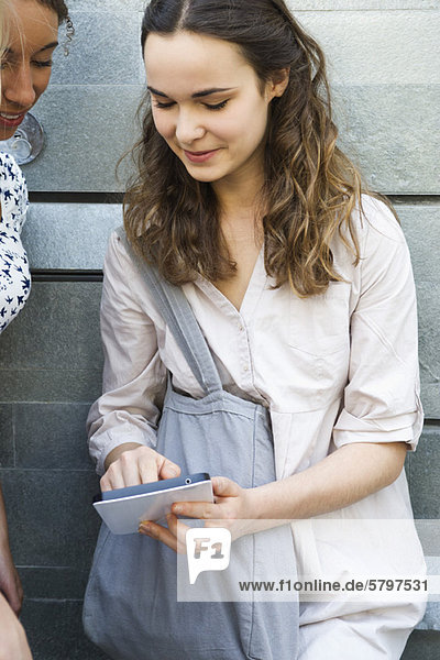 Junge Frau zeigt digitales Tablett einem Freund