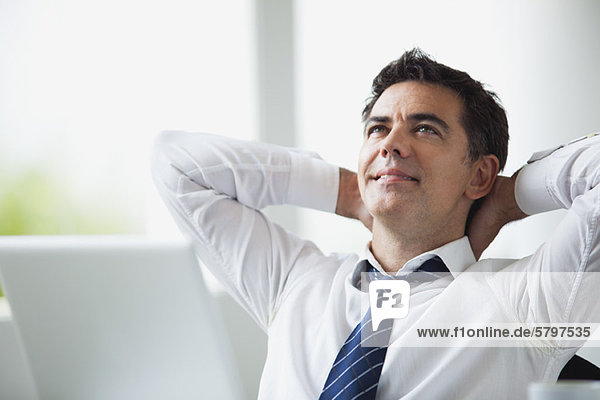 Businessman with hands behind head  smiling