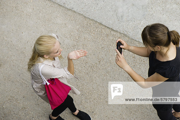 Junge Frau fotografiert Freundin mit Handy  erhöhte Ansicht